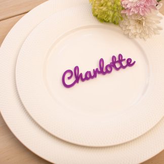 a purple acrylic wedding place name on a white plate.